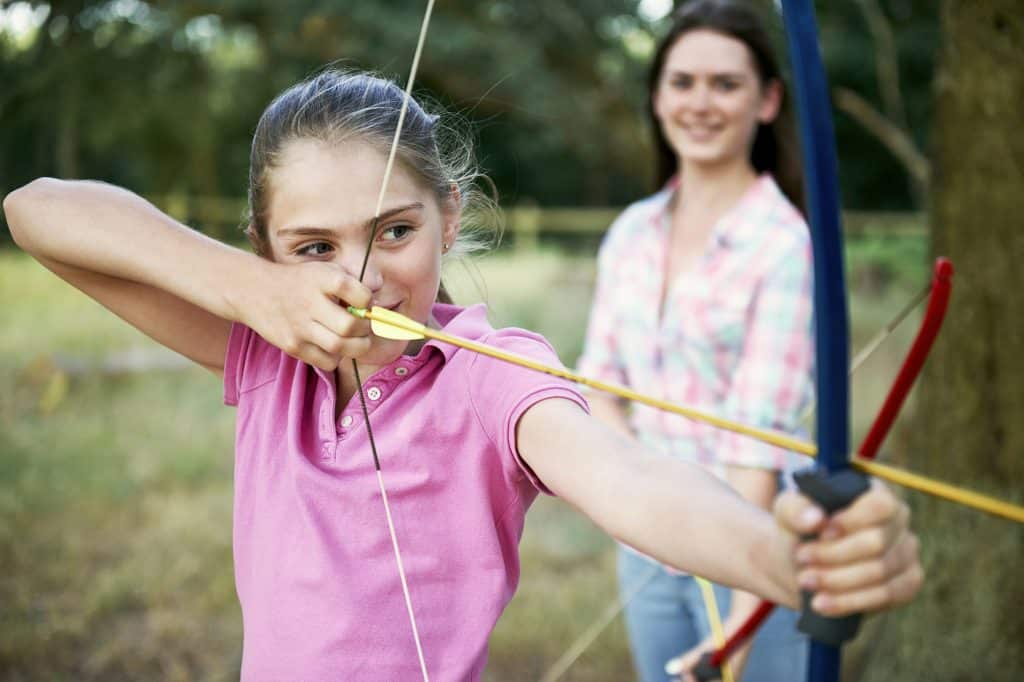 Girl practicing archery aiming with bow and arrow